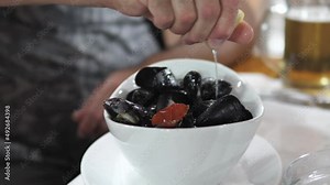 Man putting lemon juice on the freshly cooked mussels in the decorated plate in a resturant