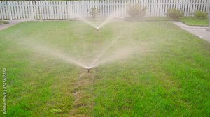 A newly installed automatic sprinkler waters the lawn. Summer grass irrigation system integrated under the lawn layer