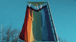 New Progress Pride Flag waving proudly outdoors on a pole, symbolizing inclusivity and diversity across LGBTQIA+ communities, alongside other pride flags and their unique representations
