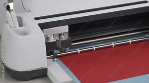 Close up Smart Cutting machine for home using. Plotter digital flatbed cut out details on red cardboard on blue mat. DIY manual paper craft, making gift for family. Creative Hand crafting project