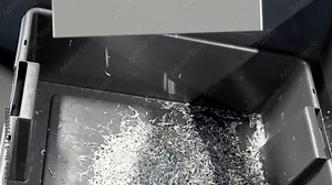 Waste metal chips, shavings or swarf being extruded out of the CNC machine into the box.