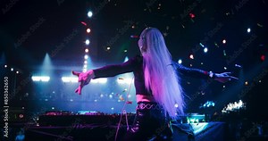 Girl Performing at a DJ Concert Live on Stage with Falling Confetti. Talented Music Producer Dancing, Mixing Energetic Dance Hits on Turntables. Young Female Engaging with the Crowd. Back View Footage