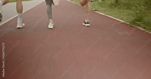 Three friends jogging in the park. They are running on a red track and enjoying the benefits of an active lifestyle.