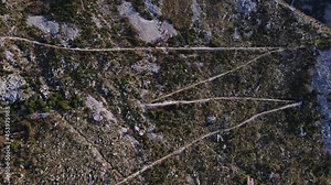 Serpentine ground road on boundless steep mountain slope with red roof houses in National Park Lovcen at spring sunlight bird eye view