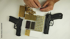 A man loading handgun magazine with 22lr ammunition on the white background. Stock Video