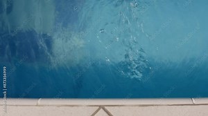 The edge of a swimming pool showing the water's surface and part of the tiled poolside