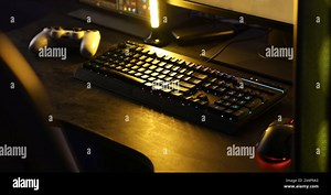 Playing video games. Computer monitor, keyboard, mouse and wireless controller on table indoors Stock Photo - Alamy