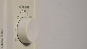 A hand turning on and adjusting the home heater temperature on a wall mounted control knob, Stock Video