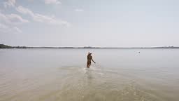 back view joyful slender girl running to swim in beautiful lake...