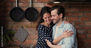 Happy loving young married family couple cuddling indoors, looking in distance dreaming or visualizing common future, feeling excited of new beginning in own dwelling, showing romantic relations.