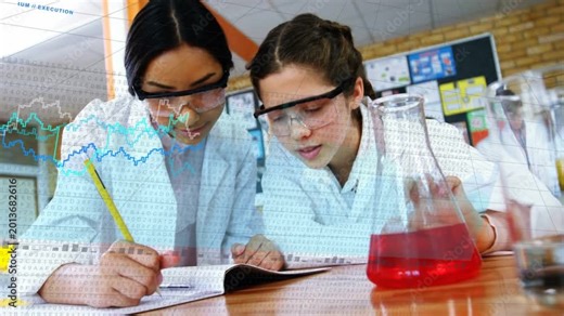Two students leaning over lab notebook documenting red flask for lab as blue charts crossing torsos