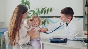 Male Doctor Pediatrician Using Stethoscope Listen to the Heart of Happy Healthy Cute Kid Girl at Medical Visit With Mother in the Hospital. Mother With Kid at Visiting Pediatrician.