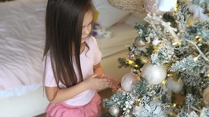 Little girl decorating christmas tree at home