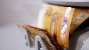 Euro currency on counting machine. 50 euro banknotes counting in the machine. Counting mechanism is processing euros. Female hand taking money. Close-up.