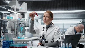 Laboratory expert analyzing batch of blood samples for disease research clinical testing. Female scientist in lab doing research on sanguine fluid vials for testing, camera A