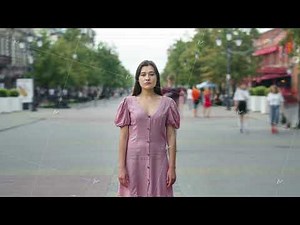 Zoom-out time lapse of pensive Asian girl standing outdoors in busy street and looking at camera