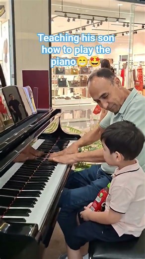 father and son are playing the piano