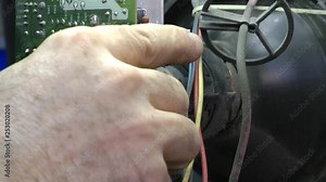 electrician repairing an old television tube and a circuit board in his workshop.