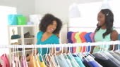 friends dancing along clothing rack together