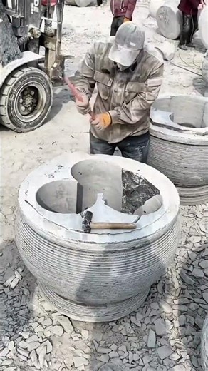 Carving and shaping large stone planters with hammers and chisels to create detailed floral designs