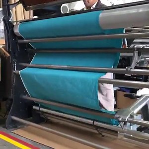 Did you know some of our customers prefer to receive their fabrics rolled on tubes (in the industry we call these ROTs)! This is the process of setting up a new ROT for an order of one of Carolyn Friedlander's Architextures prints. The fabric loops through all those metal bars to keep the tension even and the final product aligned and wound nicely. #aroundrobertkaufman | Robert Kaufman Fabrics