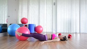 Asian woman trying to lose weight and doing stretching fitness exercise on fitness ball abdominal muscles with exercise ball in gym.
