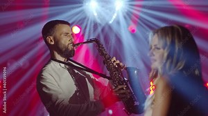 Musical band group of three people playing song, performing on concert musician stage with lights. Shooting a music video. Singer vocalist girl, saxophonist sax, dj man. Actors dancing, singing