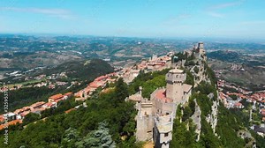 Aerial view on medieval fortress on top of the mountain, fortifications, in the background mountains and the city. The concept of the best places for tourism and holidays in Europe. San Marino, Italy