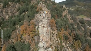 Circle drone shot of cross on the top of a cliff with beautiful forest behind