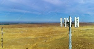 4k done footage flying closely by a cellular tower surrounded by golden hills and blue skies. Filmed at 60 FPS