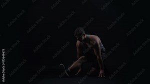 Fit young man with muscular physique doing stretches to improve flexibility
