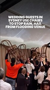 Wedding guests in Sydney use chairs to stop rainwater from flooring outdoor venue amid severe storm
