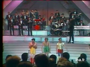 214K views · 4.4K shares | Les Charlots déguisés, chantent en direct sur le plateau "L'apérobic" ; accompagnés par l'orchestre de l'émission et des danseuses mimant une séance d'aérobic tandis que Coluche se mèle aux choristes. | Coluche | Facebook