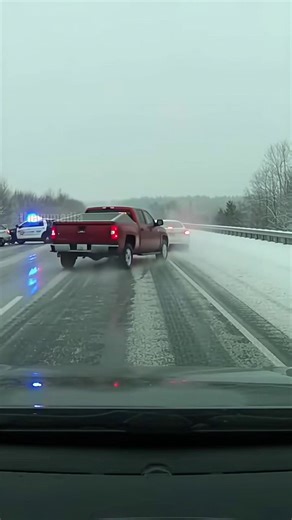 I-80 Highway, Illinois - January 14, 2025. A terrifying dashcam video shows a routine police blockade becoming a disaster zone on a patch of black ice. As state troopers diverted traffic, a red pickup truck lost control, spinning at high speed and slamming into a white sedan. The force of the impact shoved vehicles into the parked cruisers. An officer diving for safety over the guardrail was narrowly missed by another car. Miraculously, everyone involved survived with minor injuries. This video 