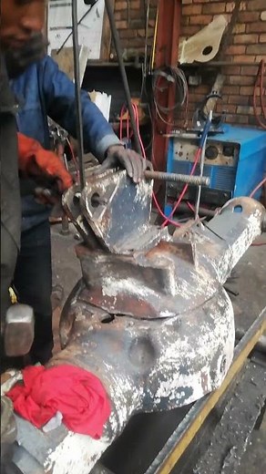 HAMMERING DIFFERENTIAL HOUSING TOP IN ADJUSTING CATERPILLAR'S AXLE IN MECHANICAL WORKSHOP