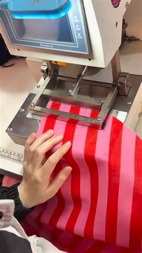 Fraying the edges of red and pink striped fabric automatically using an industrial fraying machine
