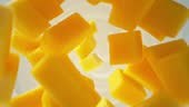 Super slow motion of mango pieces falling into yoghurt cream. Filmed...