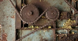 Closeup of rotating gears and chains on industry machine, Metal gears slowly moving chain on ribbon making machinery - close up tilt up