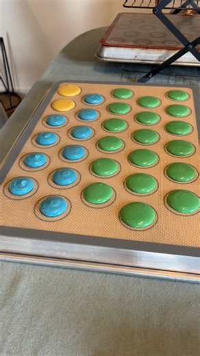 Bakes By Kristen on Instagram: "Rapid macaron piping action 🟡🔵🟢 Home baker, macarons, macaron piping, yellow macarons, Swiss macarons, green macaron, blue macaron, rainbow cookies, French pastry"