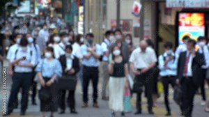 TOKYO, JAPAN - JUL 2020 : Crowd of people at the street near Shinjuku station in rush hour. Commuters wearing surgical mask to protect from Coronavirus (COVID-19) in hot summer. Blurred slow motion.