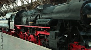 Heavy industrial steam locomotive train red and black engine wheels is at the railway station. Wide angle, prores, slow motion