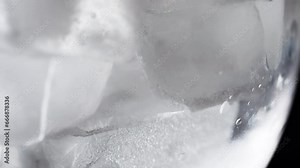 Ice cube in dynamic motion a mesmerizing close-up view of a rotating ice cube. The facets catch and reflect light, creating an intriguing display of movement and texture. High quality 4k footage