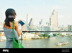 Young pretty woman tourist enjoying Bangkok cityscape skyline take video. Famous landmark shopping mall over city observation dock. Woman blogger trav Stock Photo - Alamy