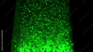 Macro shot of blurred bubbles on illuminating green background. Bubbles rotating in space, textured green bubbles in liquid solution. Concept of gel, beverage and scientific chemistry experiments