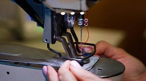 Woman using sewing machine in factory. Female hands working on tailoring industrial fabric