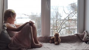 Girl sitting on a windowsill with a teddy bear