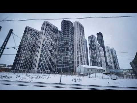 Modern skyscrapers rising above snowy urban landscape viewed from moving train in Moscow