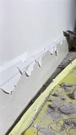 Spreading wall filler with putty knife and smoothing surface during indoor repair work task