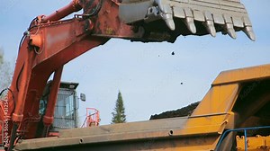 Close-up Red excavator digs an earth and loads into a yellow dump truck Stock Video