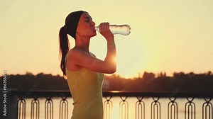 Slow motion: Running woman. Runner is jogging in sunny bright light. Female fitness model training outside in the city on a quay. Sport lifestyle. Filmed at 240 fps.